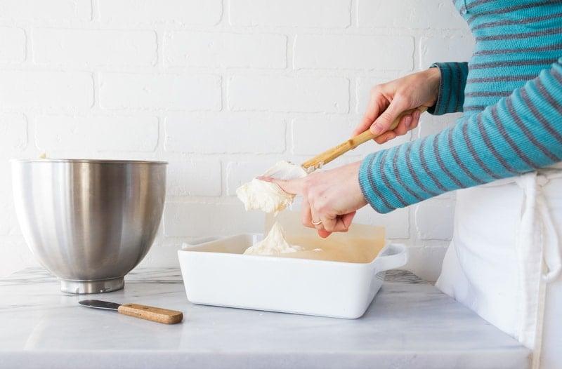 person stirring melted butter and sugar in a bowl for cookie squares