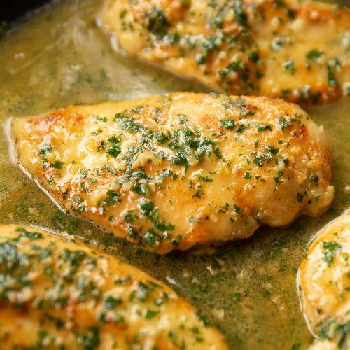 sizzling garlic butter chicken in a skillet, golden brown and garnished with parsley
