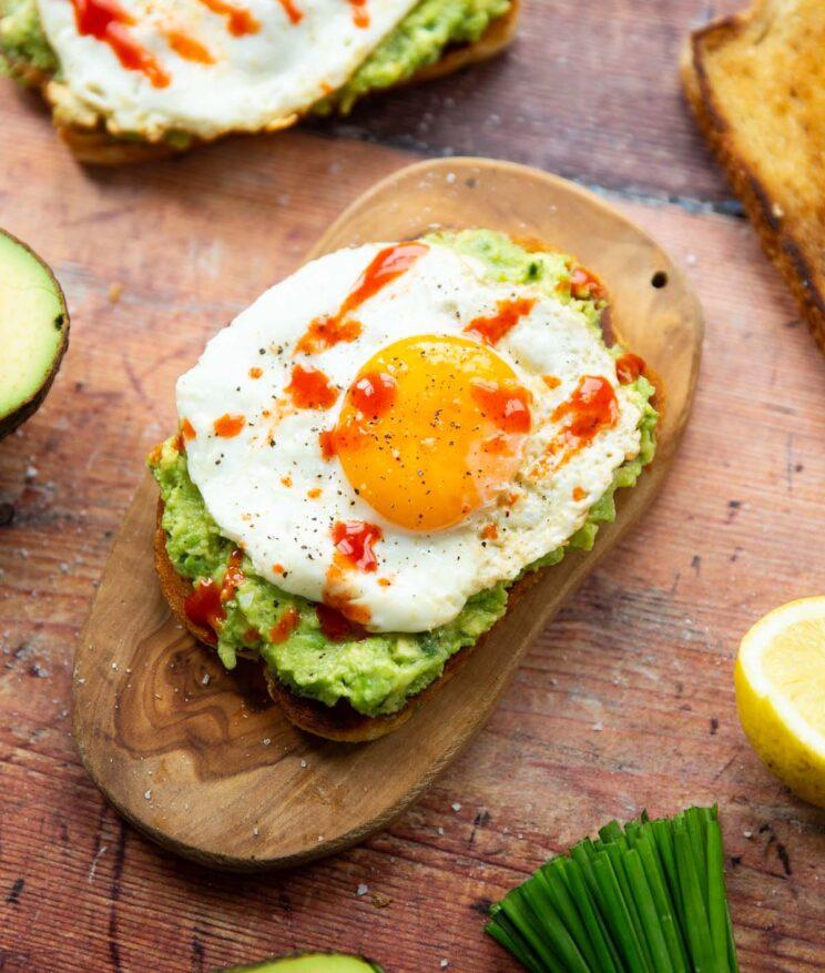 Avocado toast with hot sauce on a wooden board