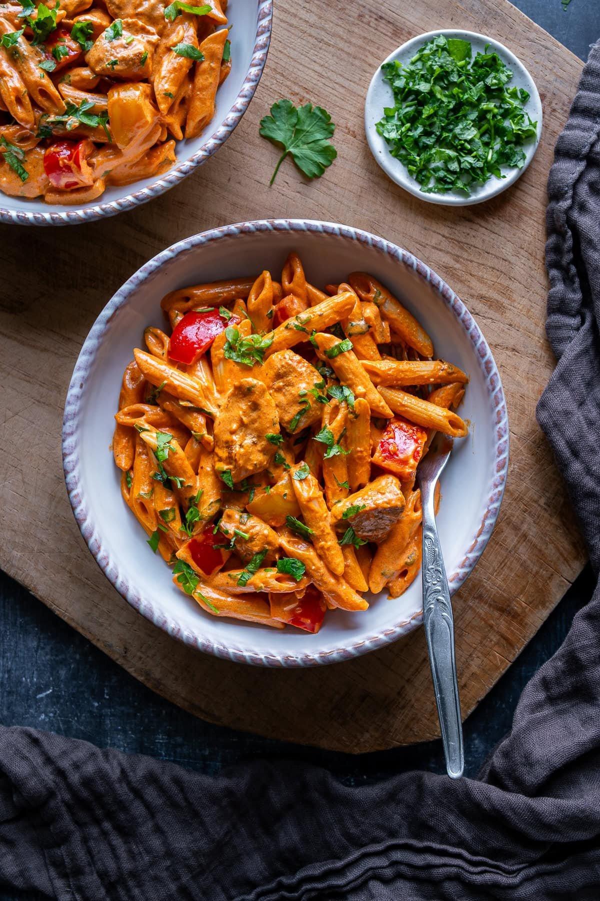 Overhead shot of creamy Cajun chicken pasta in a serving bowl, garnished with fresh herbs and Parmesan.