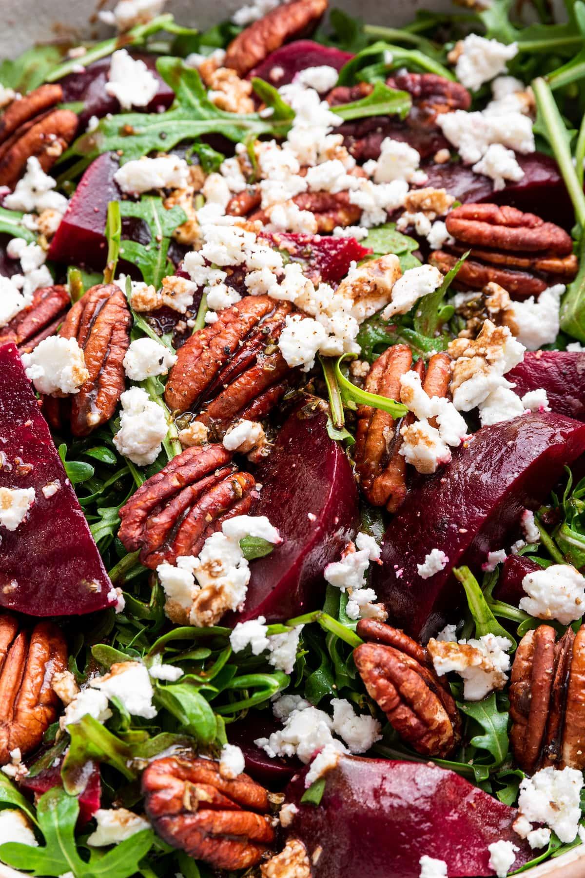 close up of arugula and beet salad on a plate, drizzled with balsamic vinaigrette