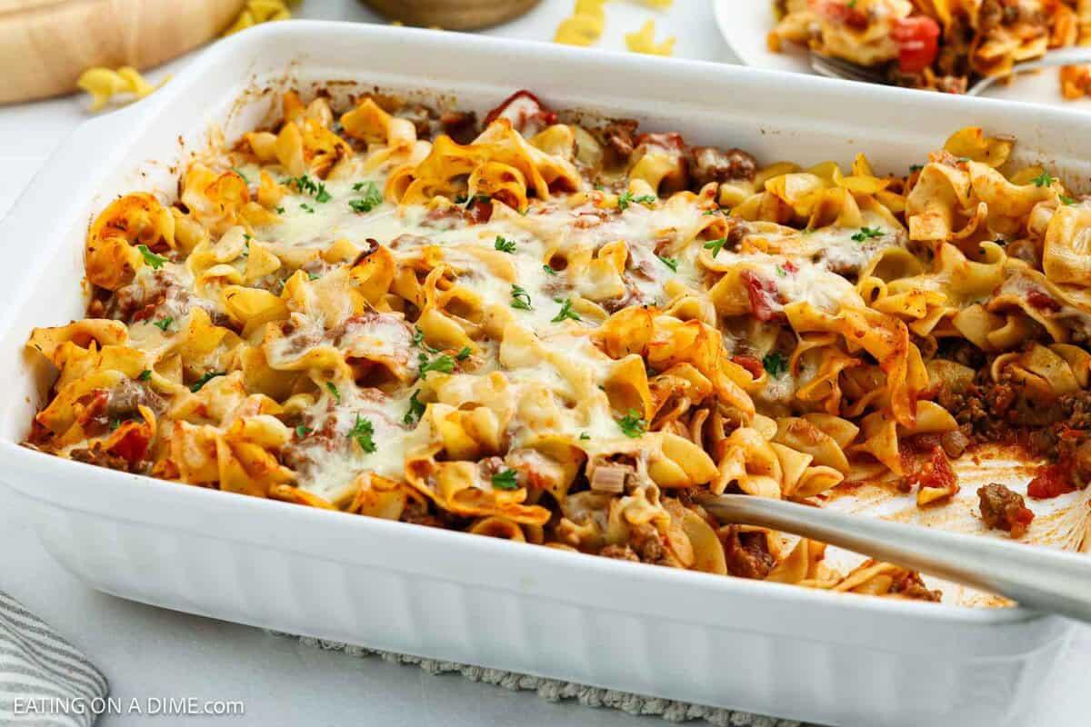 hearty creamy ground beef casserole dish with melted cheese and egg noodles, garnished with parsley