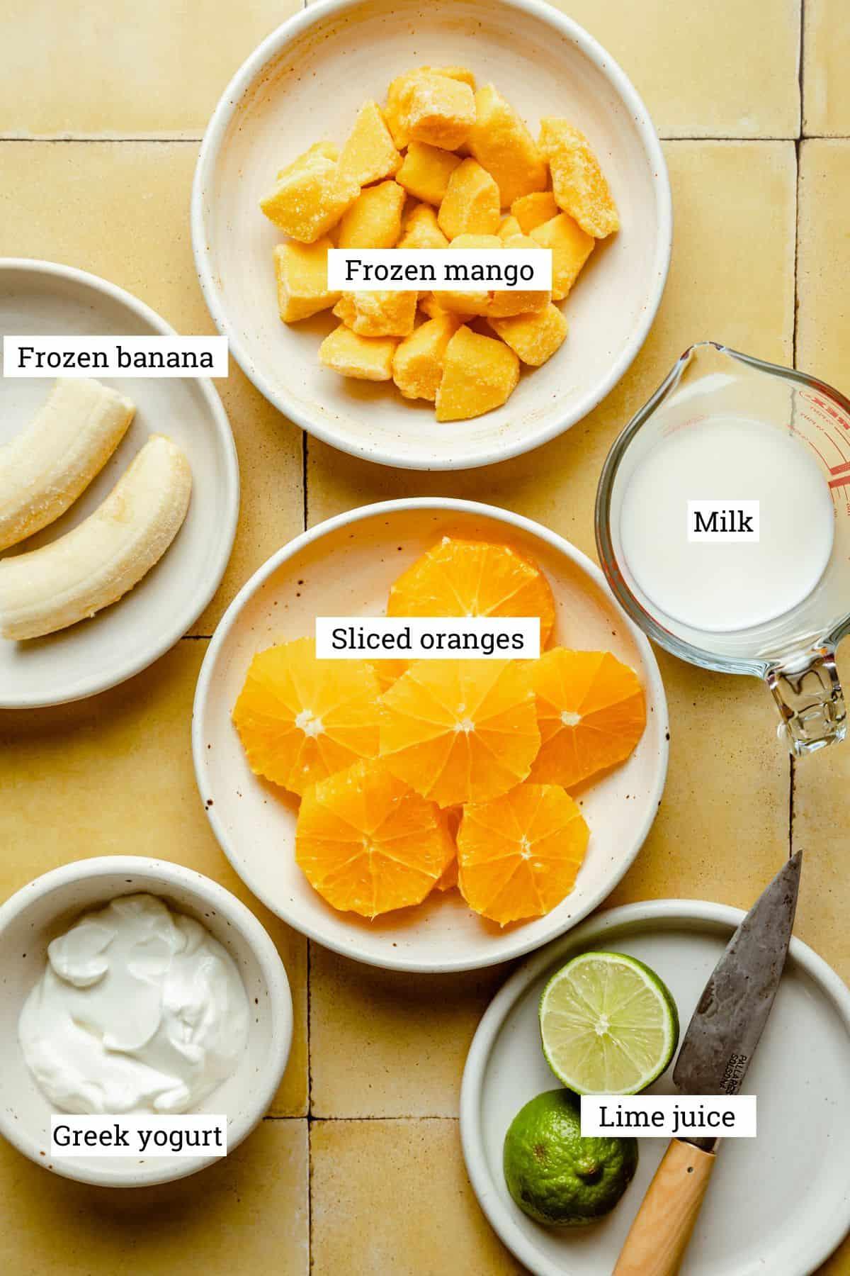 ingredients for mimosa smoothie: oranges, mangoes, greek yogurt, and sparkling wine