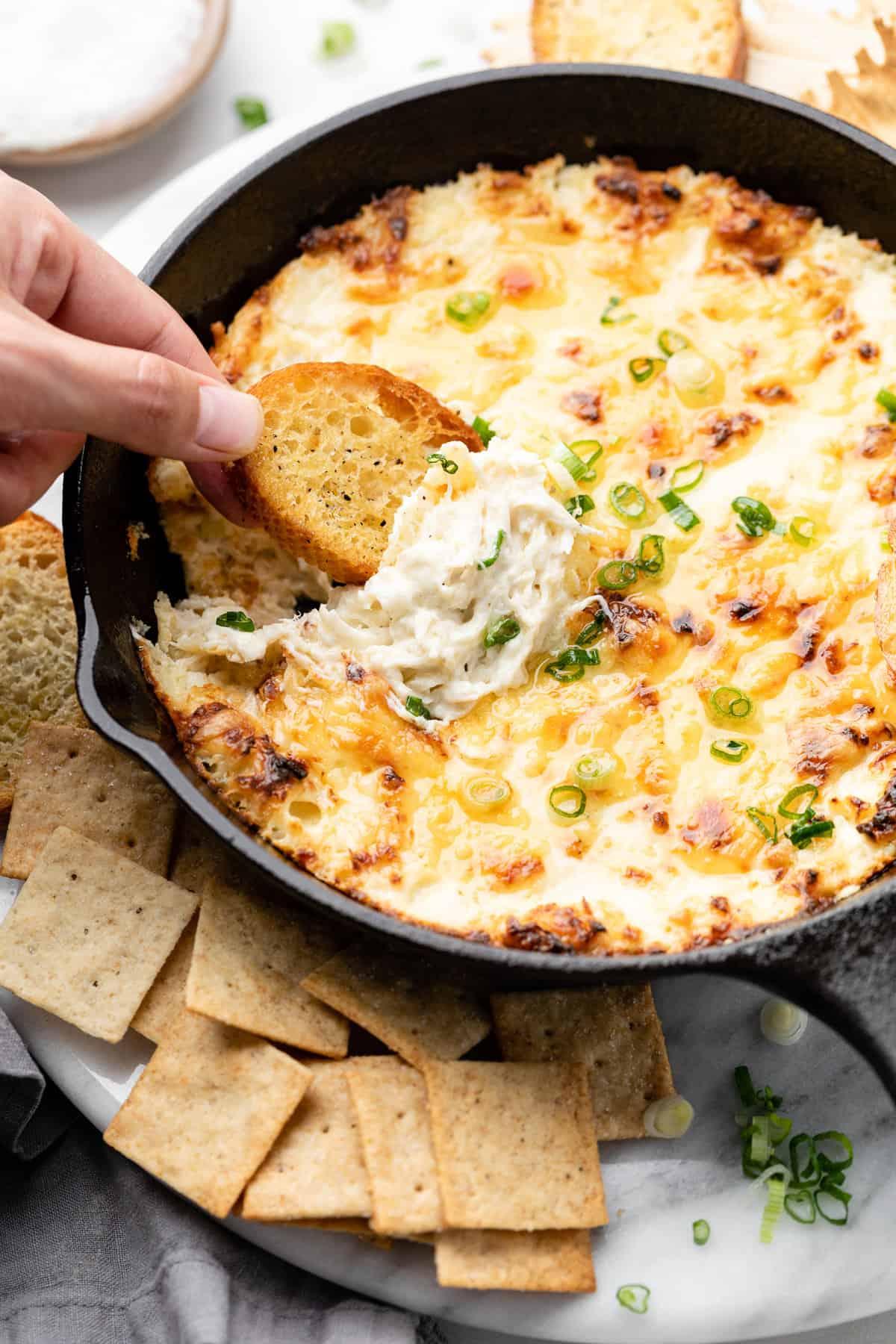 friends gathered around a table with a hot baked crab dip and other appetizers