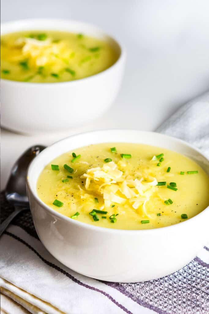 A bowl of creamy potato and leek soup topped with shredded cheddar cheese