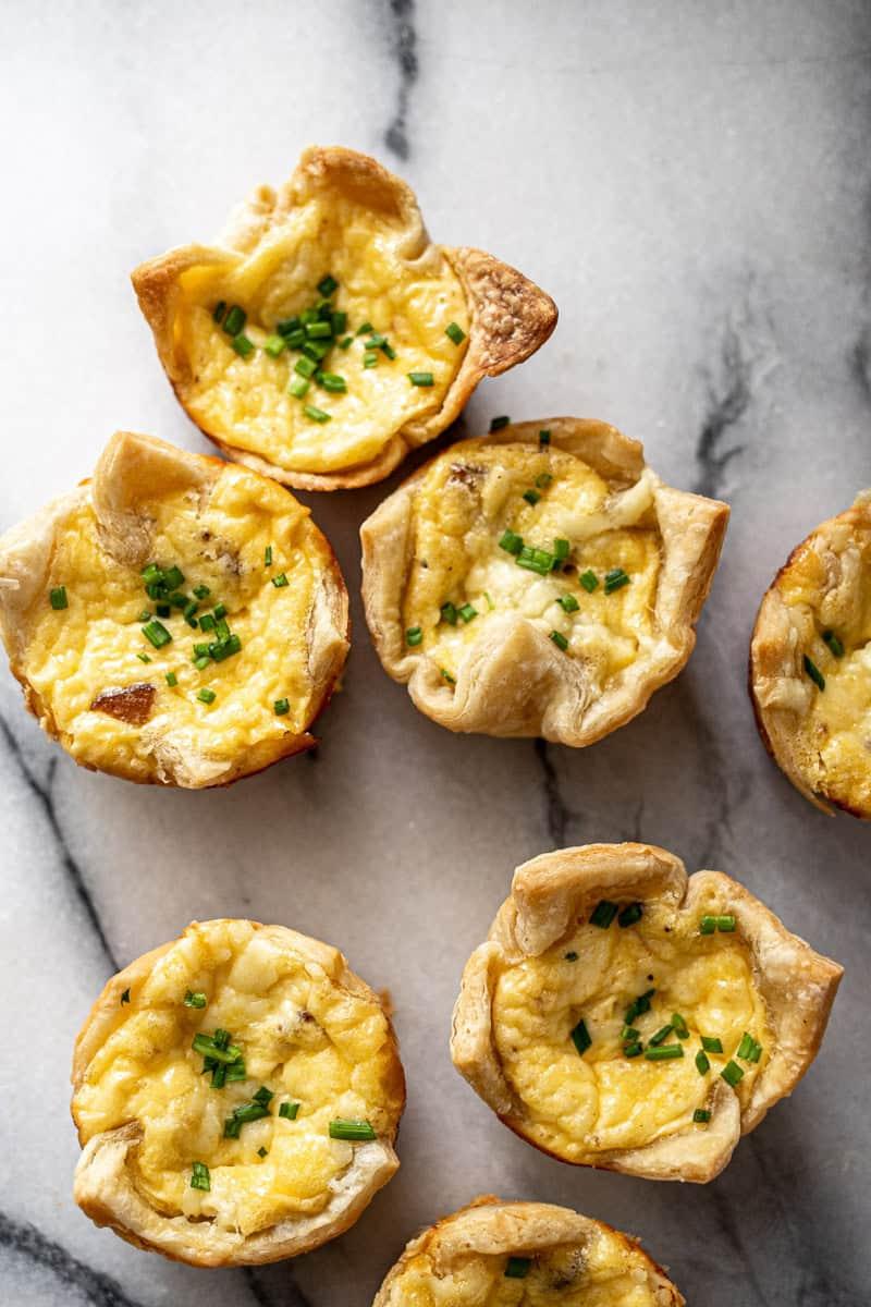 Close-up of golden brown mini quiches with visible creamy filling and flaky crust