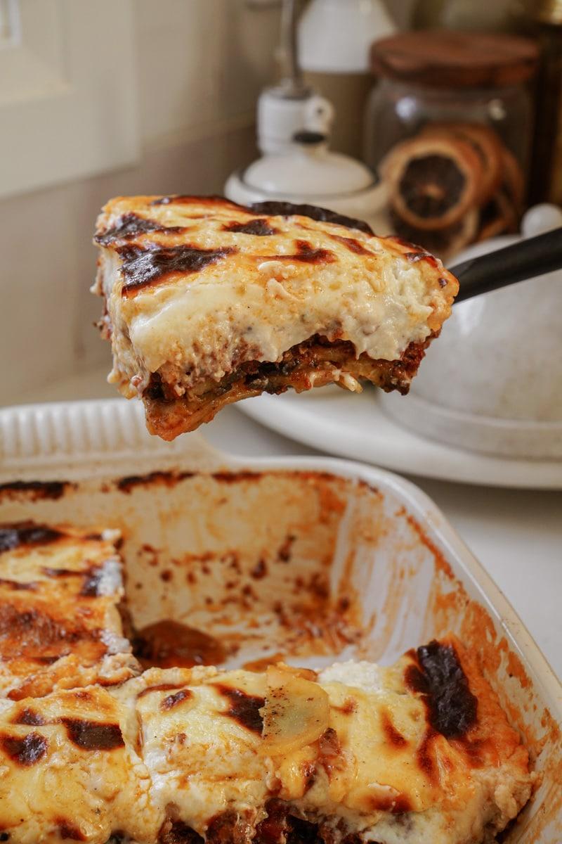 a slice of moussaka being lifted from the baking dish