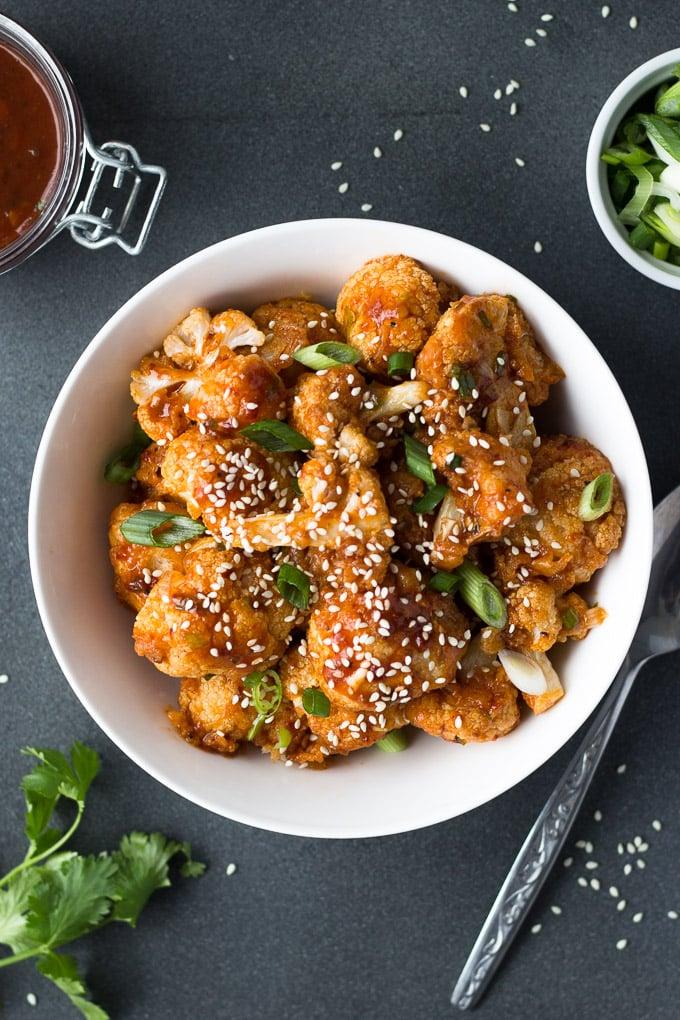 Close-up of glossy, chili-glazed crispy cauliflower on a small serving plate.
