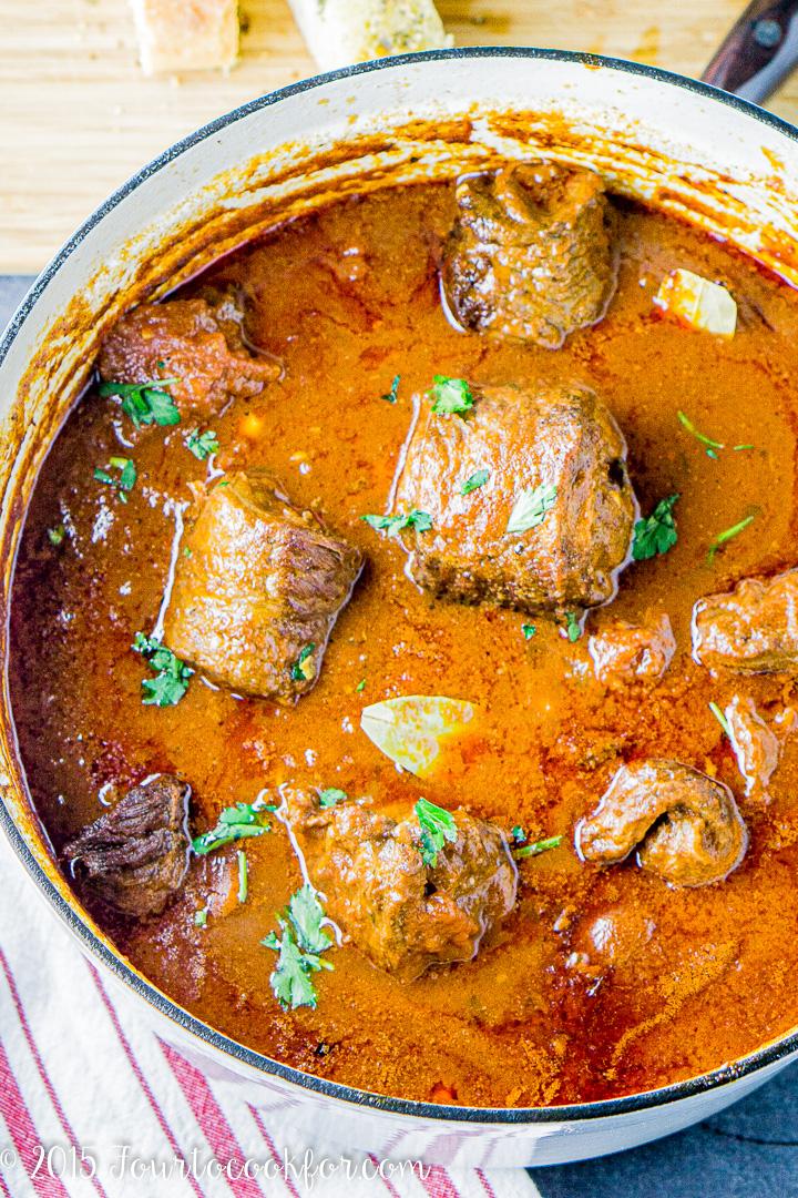 beef braciole simmering in tomato sauce in a dutch oven