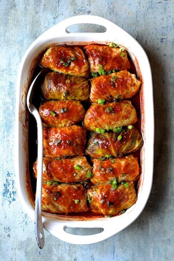 Close-up of a person rolling pork and cabbage rolls.