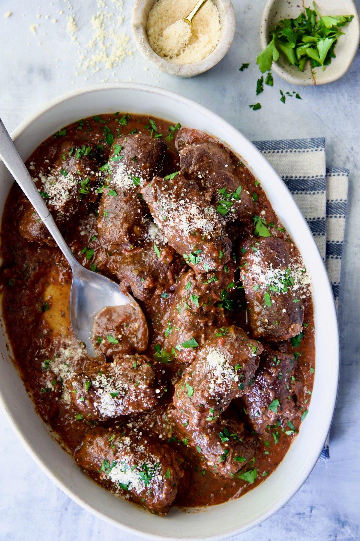 Thinly sliced beef marinating in a bowl with Italian seasoning and spices