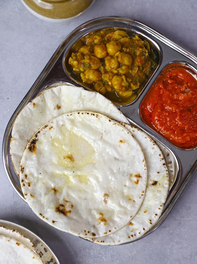Overhead shot of a stack of warm roti with a bowl of bright mango chutney