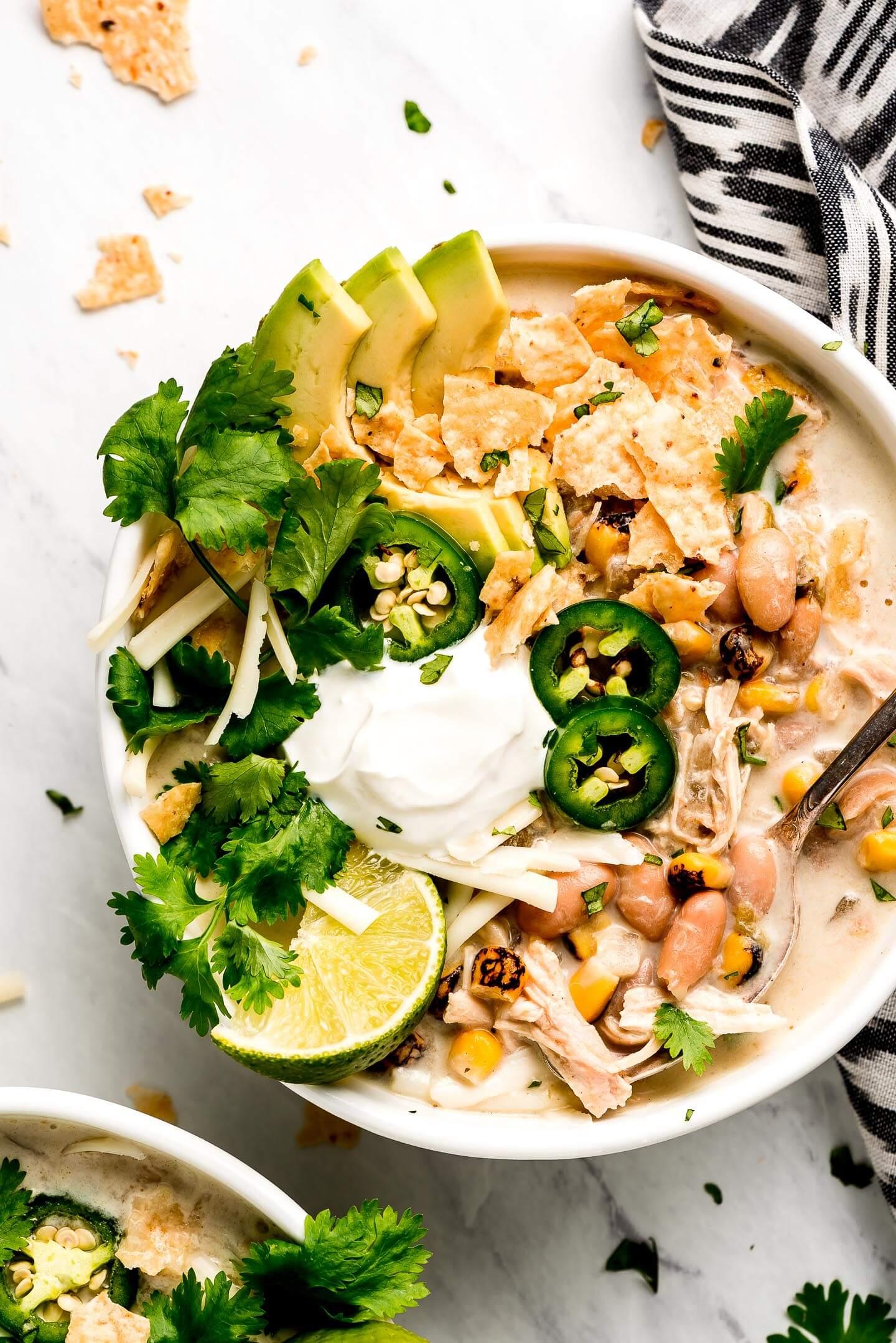 bowls of slow cooker white chicken chili stew garnished with toppings
