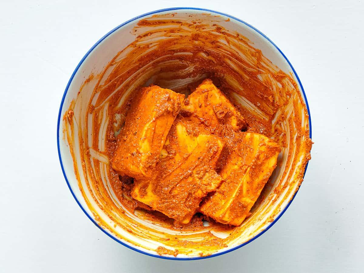 Close-up of paneer tikka marinating in a bowl