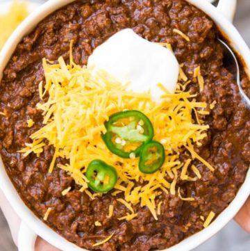 bowls of Texas chili topped with cheese, sour cream, and jalapeños
