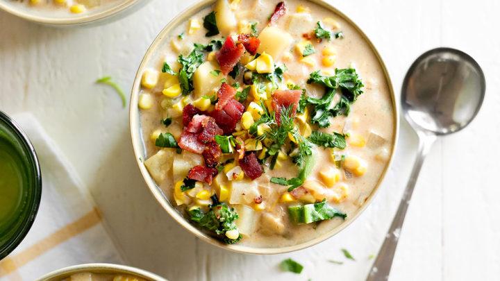 A person enjoying a bowl of grilled corn and bacon chowder outdoors