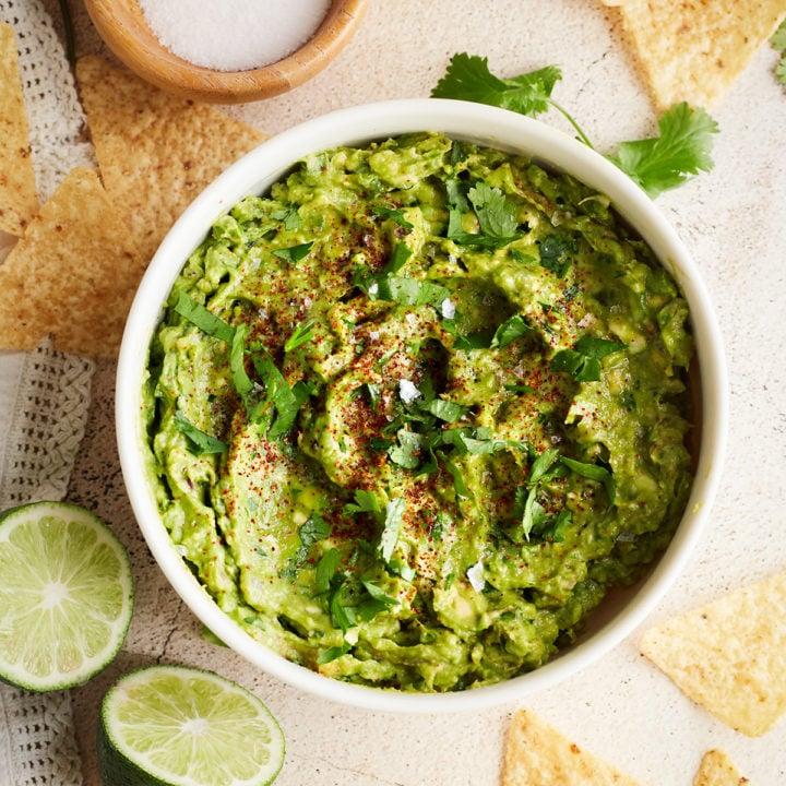 Overhead shot of a completed bowl of Sotol Guacamole, garnished with cilantro and lime wedges