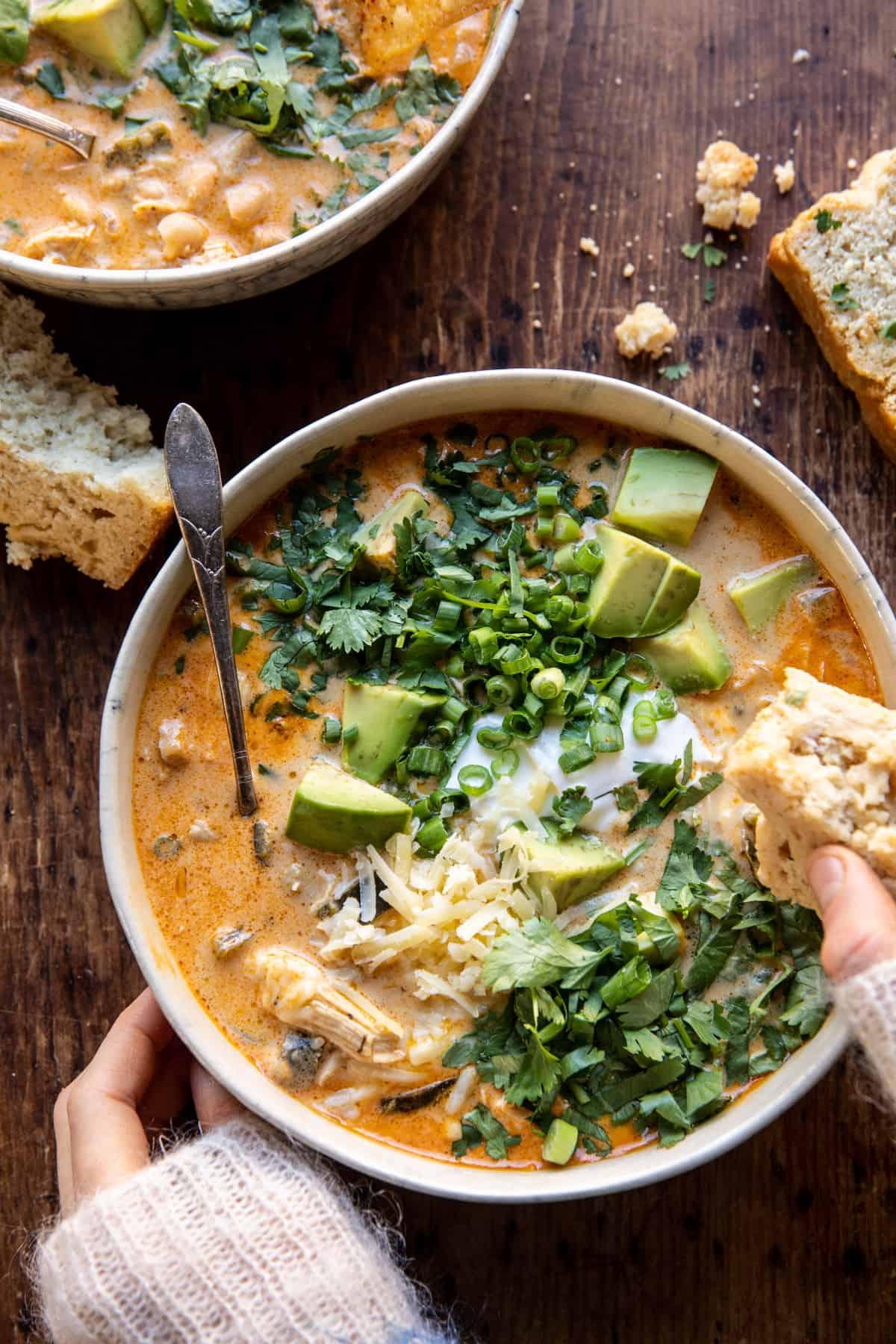 Bowl of creamy white chicken chili with toppings, cozy setting