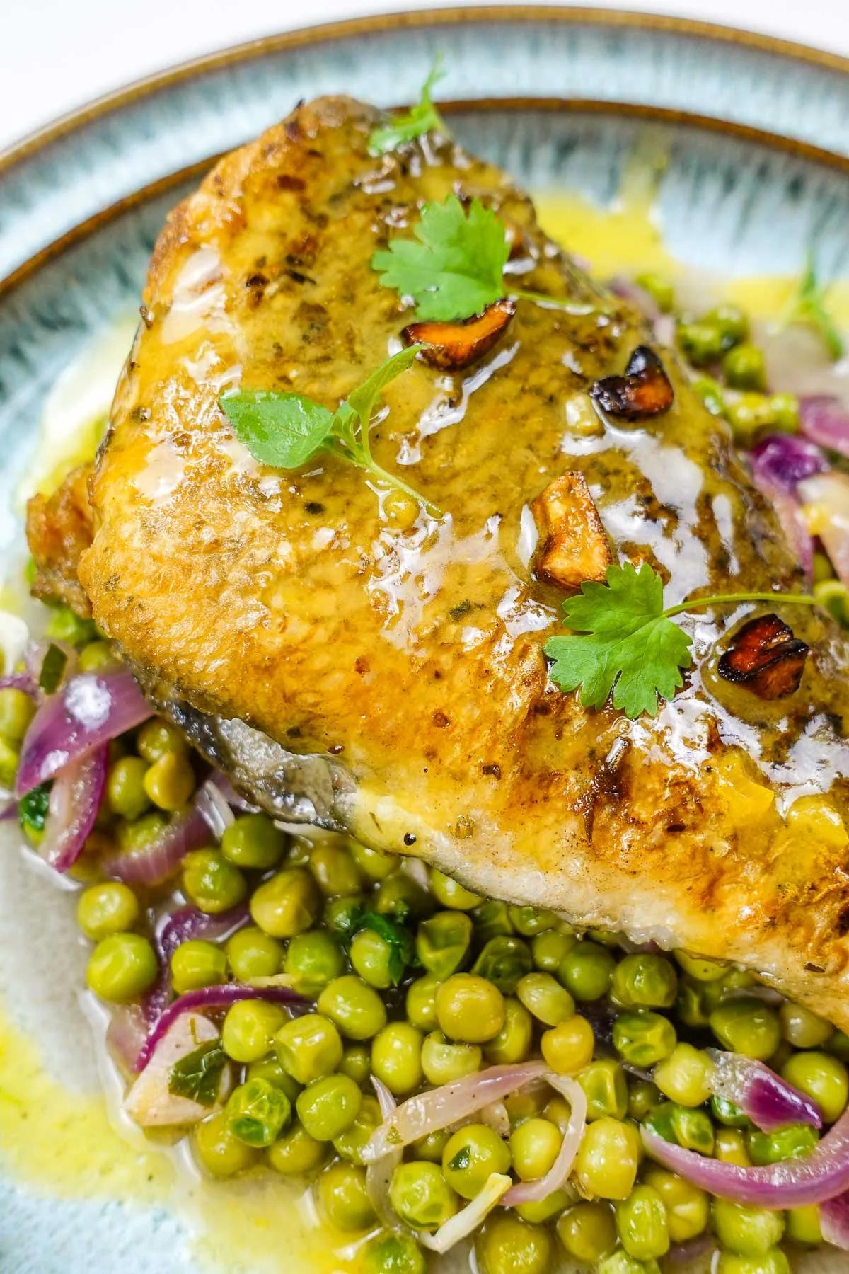 Steamed sea bream with lemon and oregano, garnished with fresh herbs on a white platter