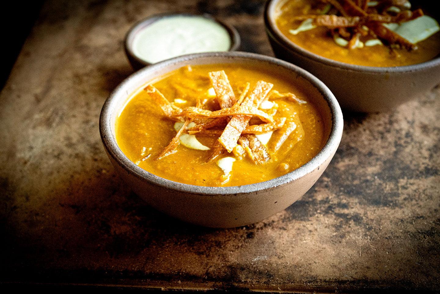 pumpkin and poblano soup being poured into a bowl
