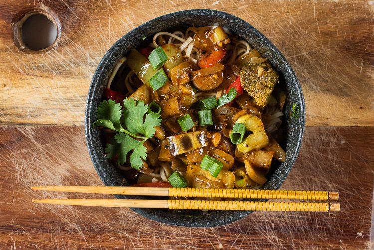 close-up of banana slices being added to a noodle stir-fry