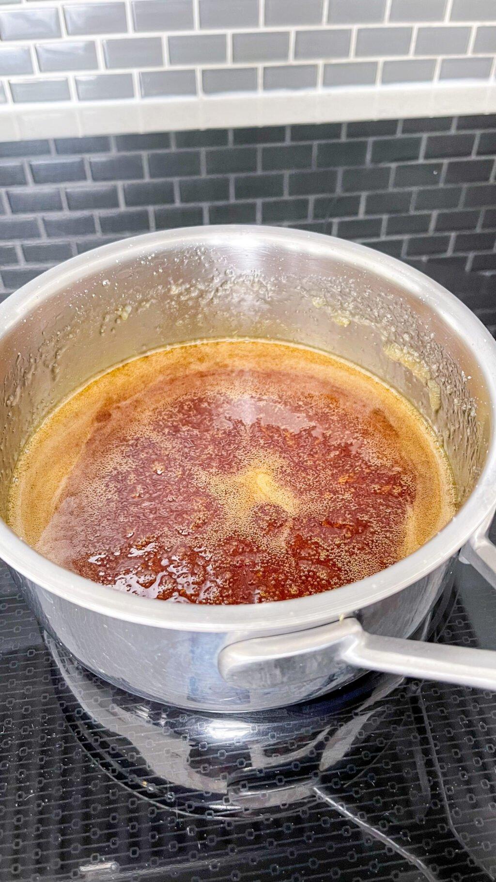 close-up of golden caramel bubbling in a heavy-bottomed saucepan on a stove