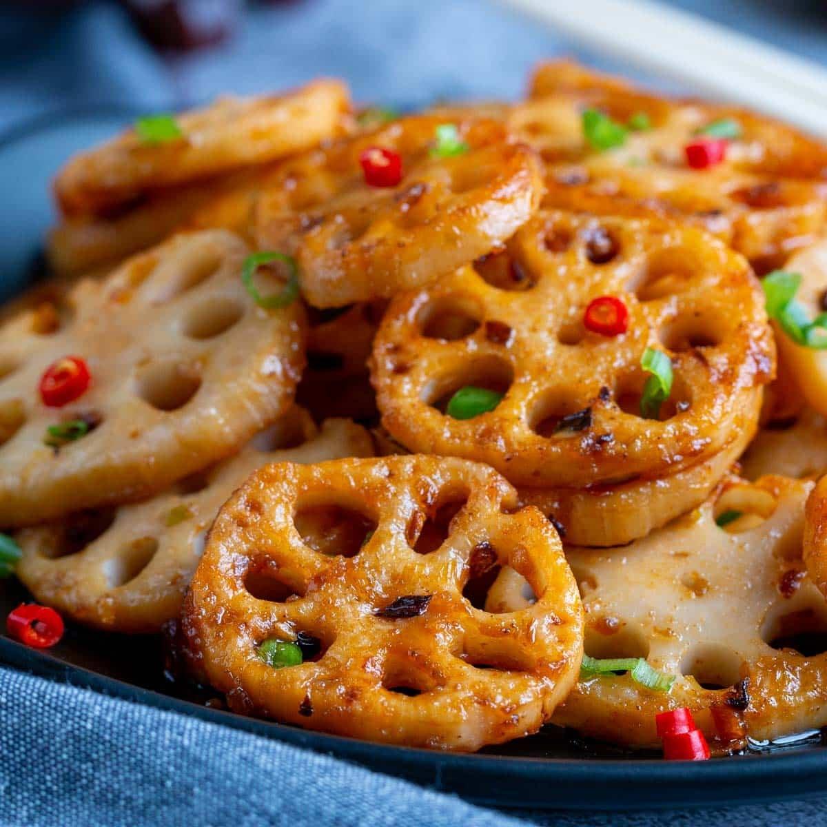sautéed lotus root with sweet and sour sauce plated beautifully with sesame seeds and green onions