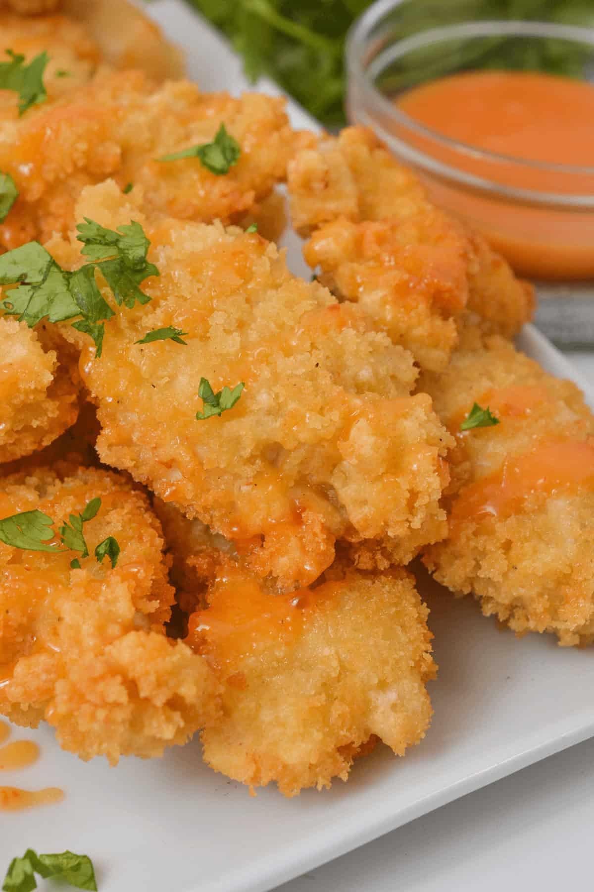 Close-up of crispy chicken pieces being tossed in a creamy orange Bang Bang sauce