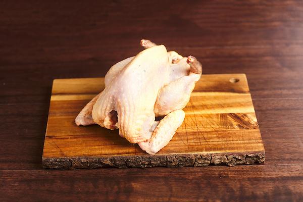 whole raw guinea fowl on a wooden cutting board