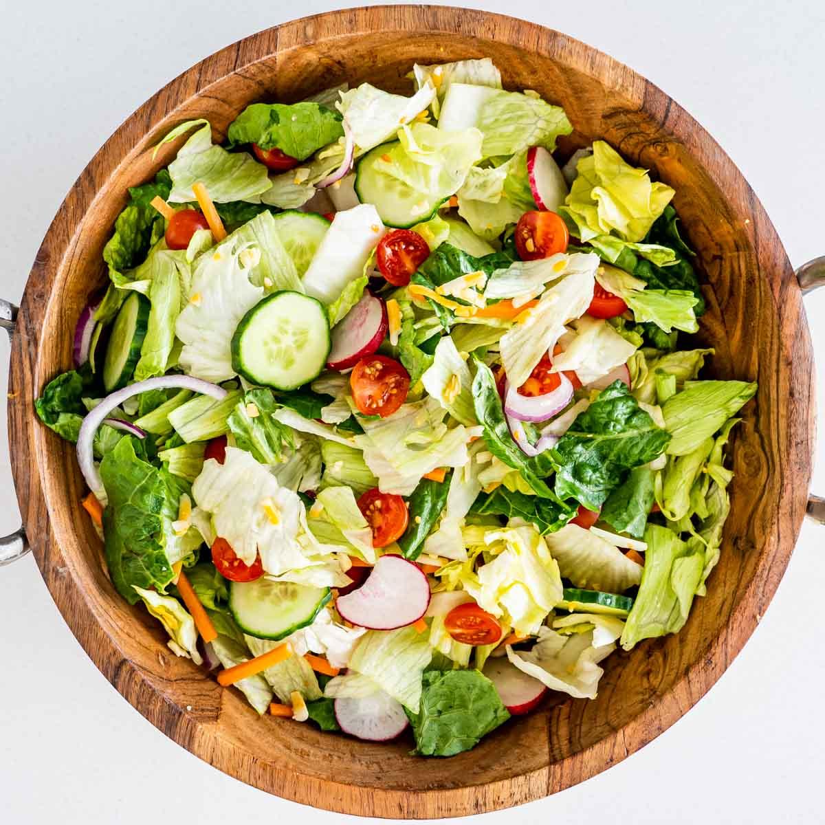 A bowl of fresh summer salad being tossed with a delicious dressing