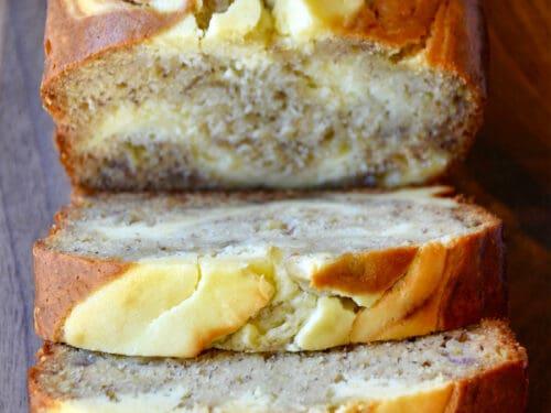 A beautifully baked banana cream loaf, sliced, with a visible cream cheese swirl and a light glaze.