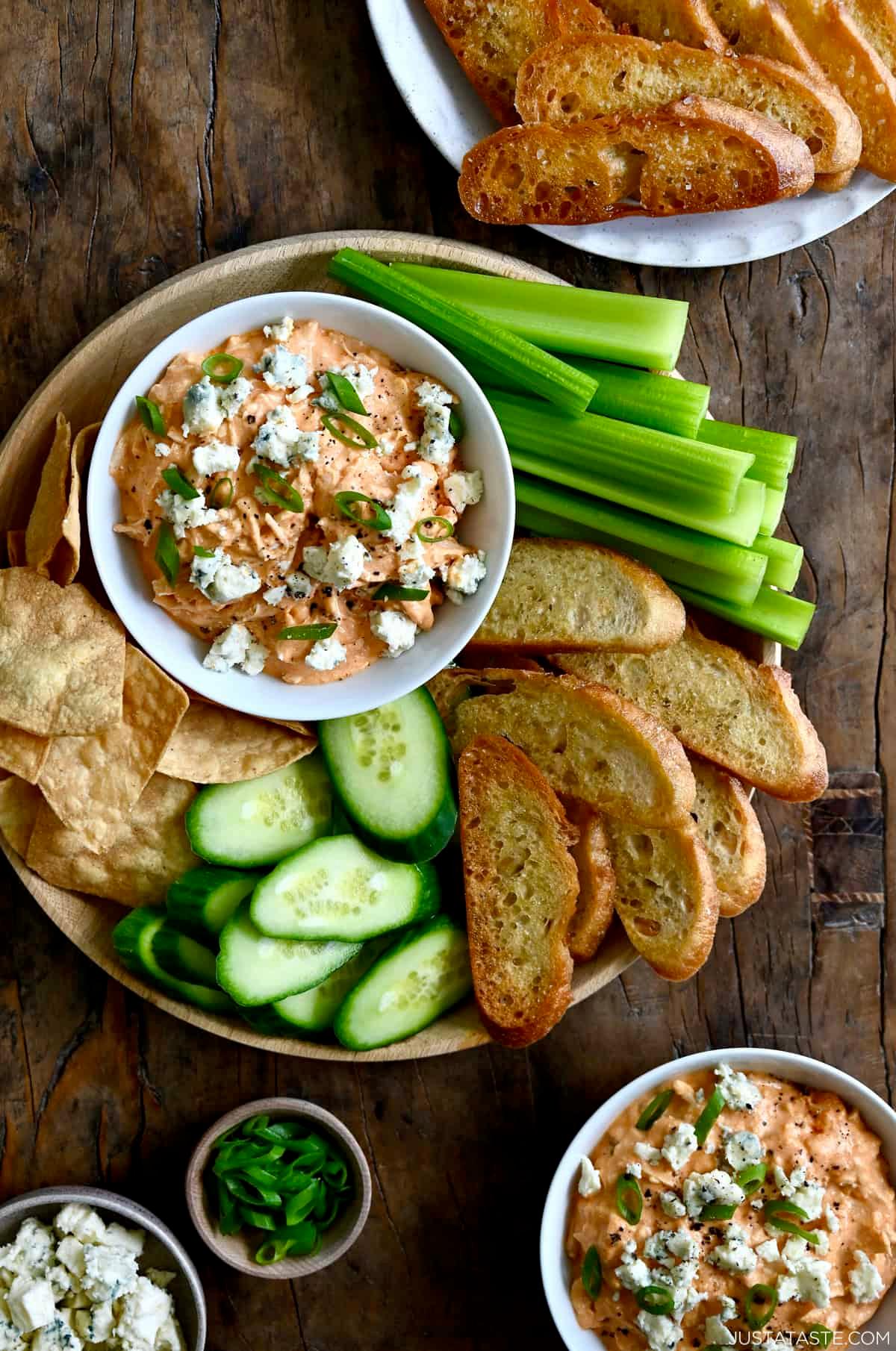 Slow cooker filled with buffalo chicken dip, surrounded by a variety of dipping items on a serving platter
