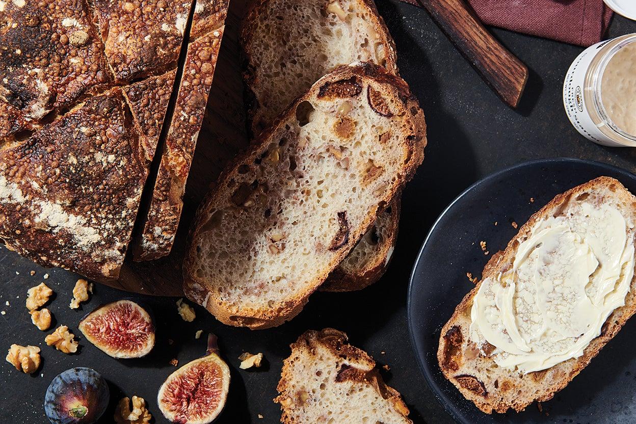 Close-up shot of a slice of sourdough bread with fig jam and walnuts, showing the texture and ingredients.