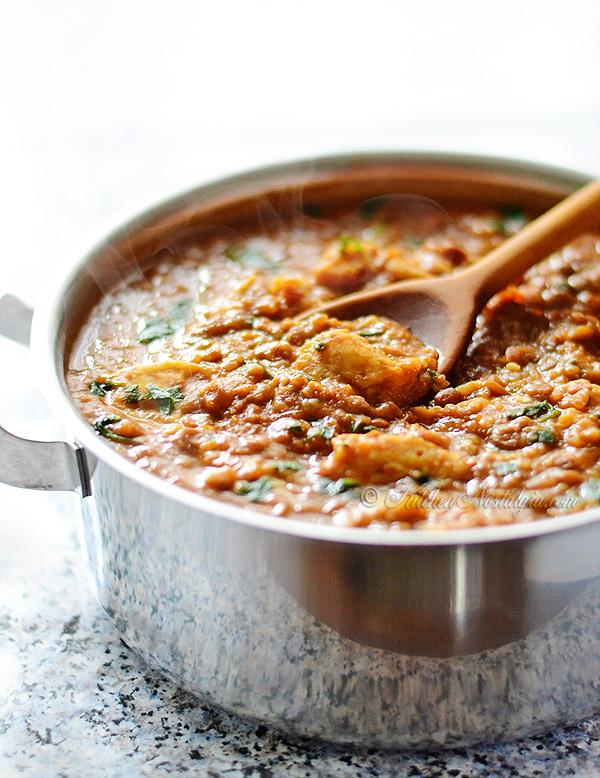 side view of lentil soup with dumplings being ladled into a bowl