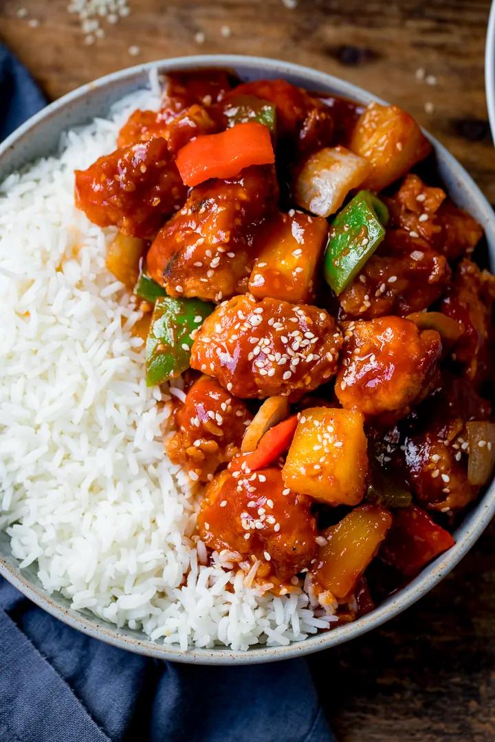 sweet and sour chicken being prepared in a kitchen with vegetables and sauce