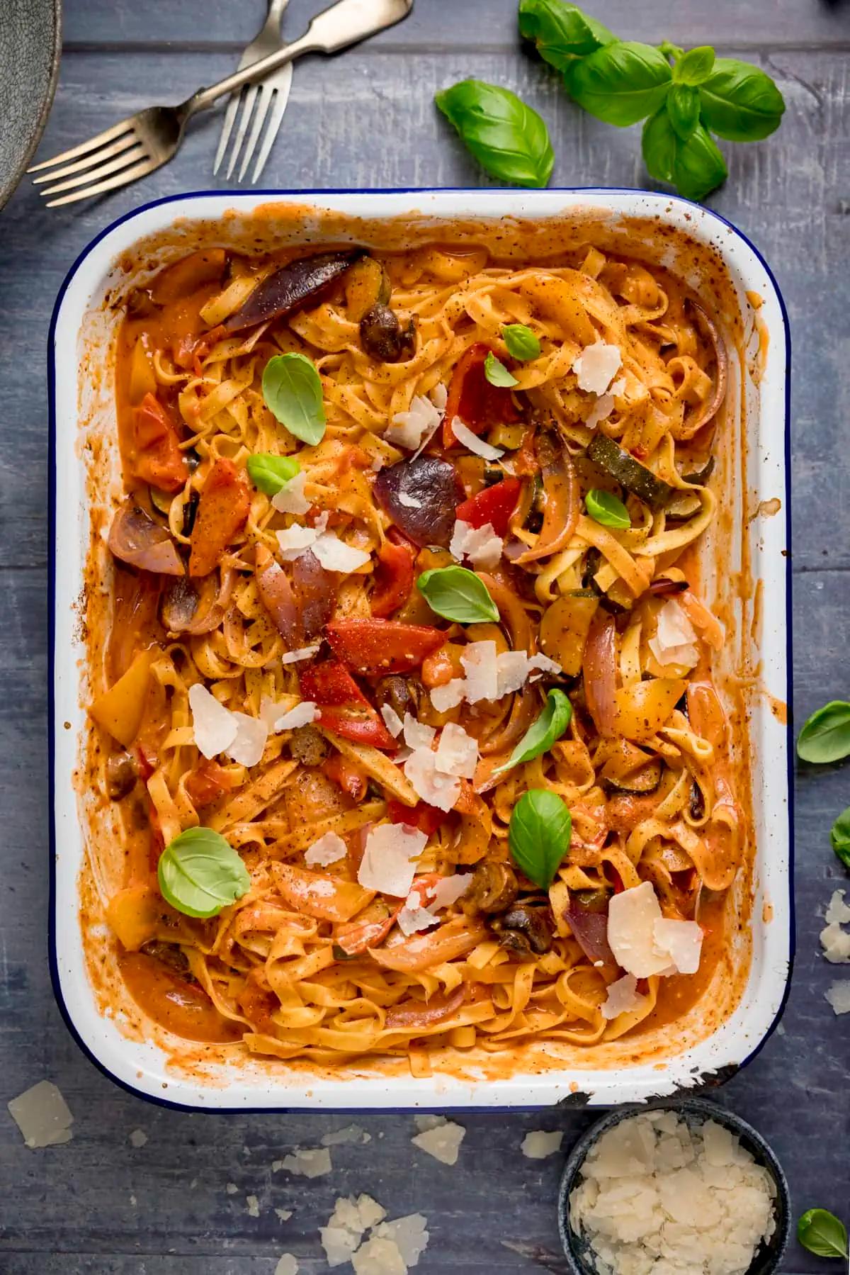 a person tossing roasted vegetables and pasta together in a pot