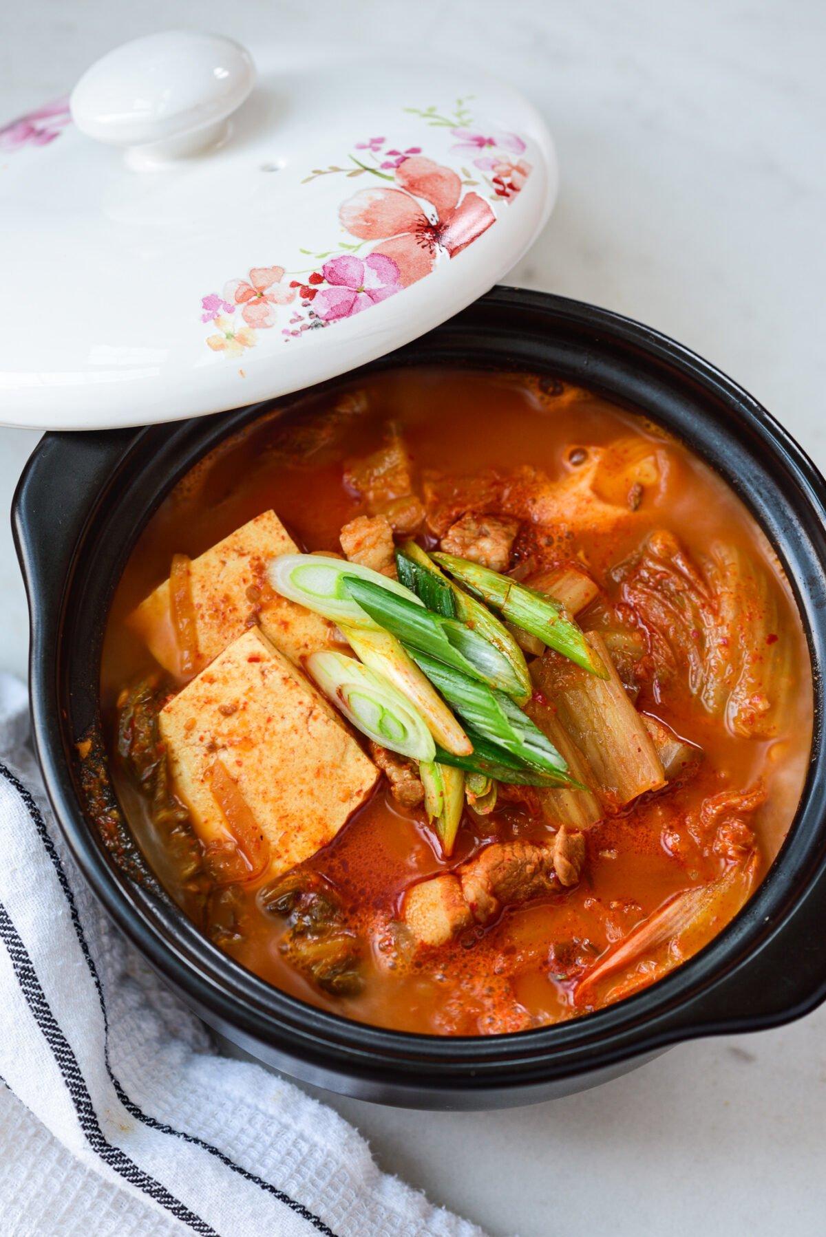 Bubbling pot of kimchi jjigae with visible tofu and pork belly