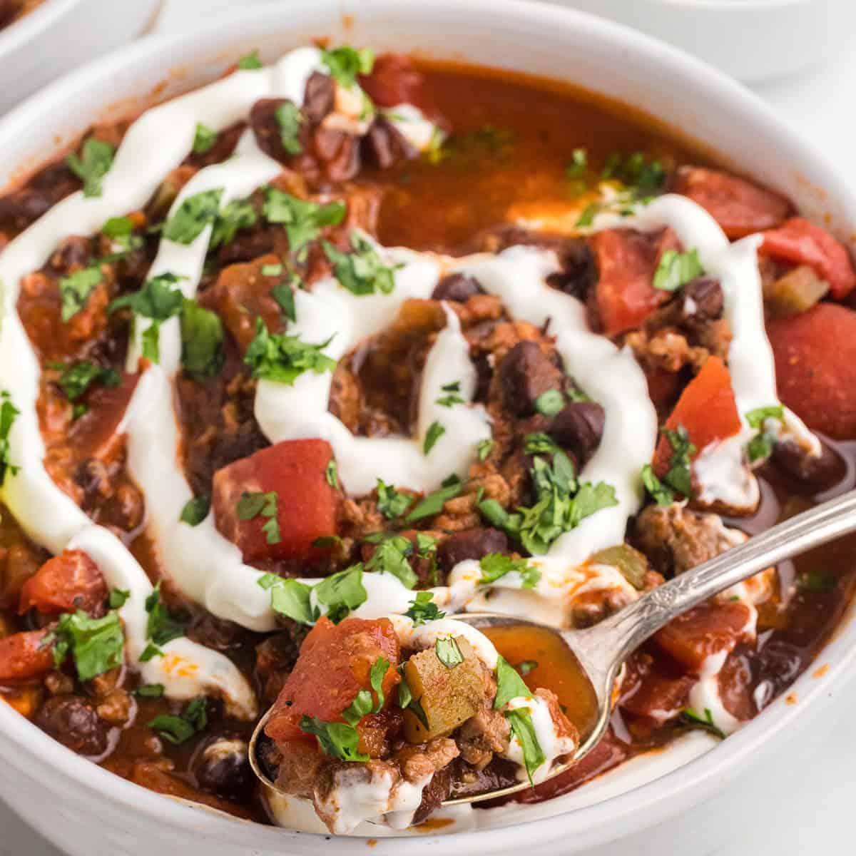 bowl of kimchi chili with black beans and corn, garnished with cilantro and sour cream
