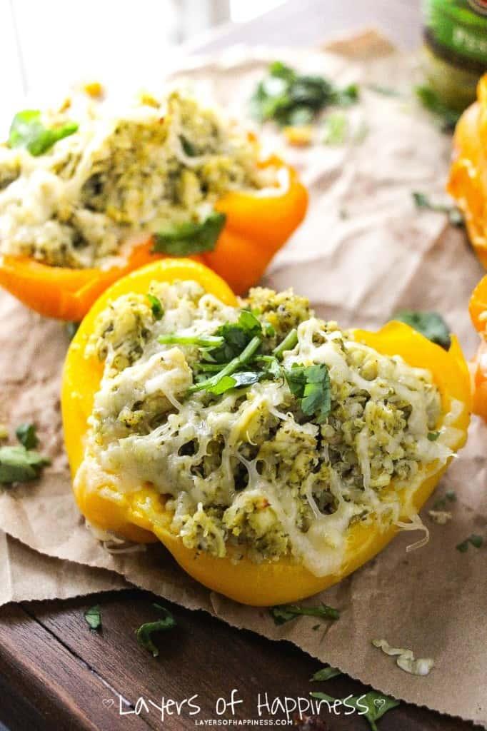 Pesto chicken stuffed bell peppers on a rustic wooden table