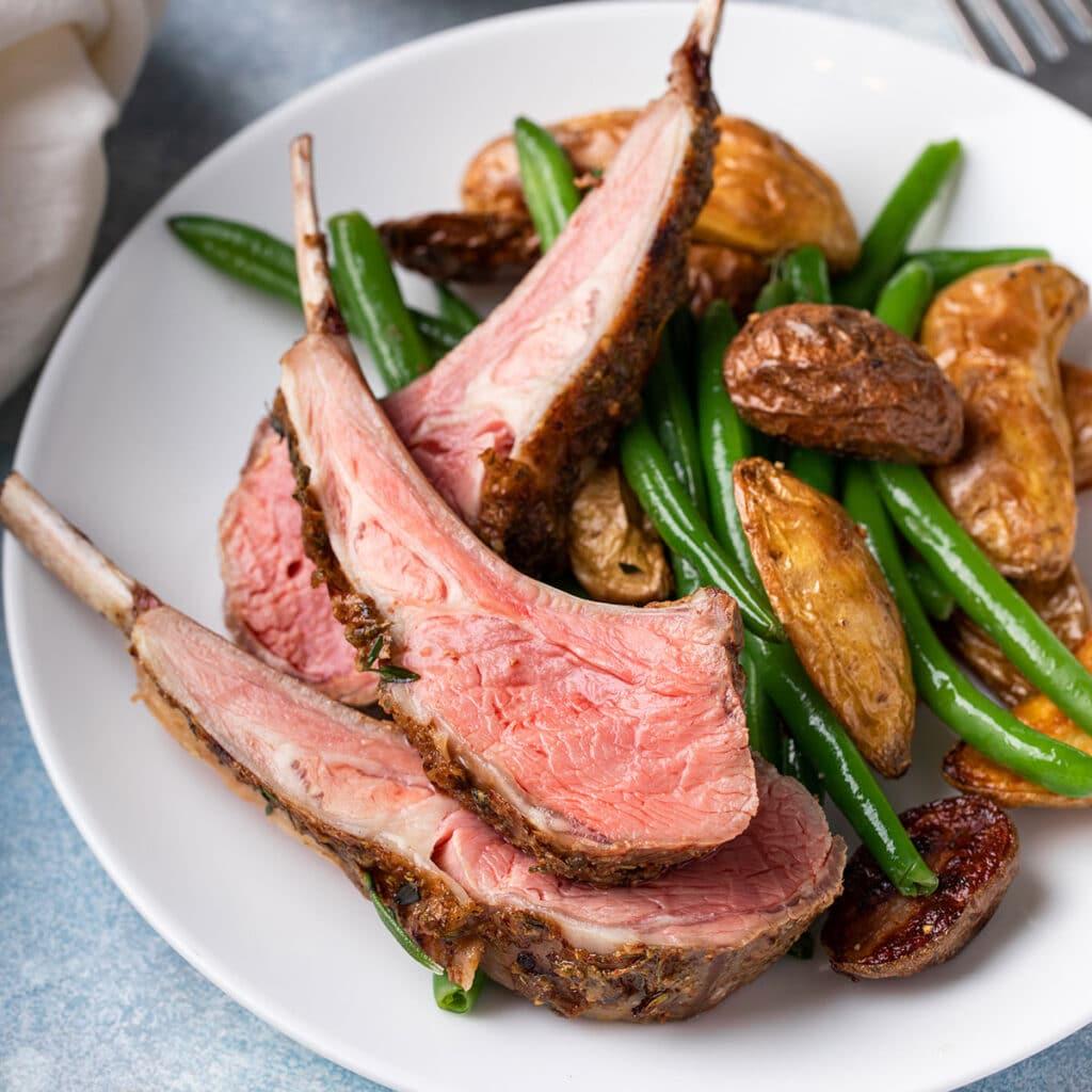 A beautifully roasted herb-crusted rack of lamb served alongside rosemary potatoes.