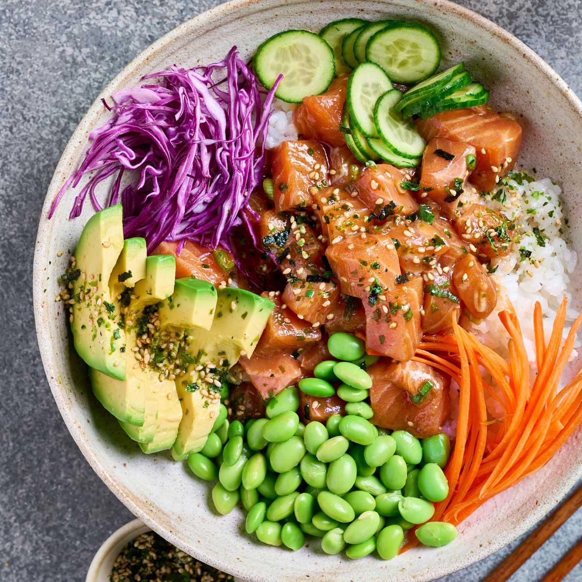close-up of a colorful and fresh poke bowl with visible salmon, cucumber, and sriracha
