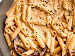 A close-up of a creamy, rich Cajun sauce simmering in a skillet with sautéed vegetables.