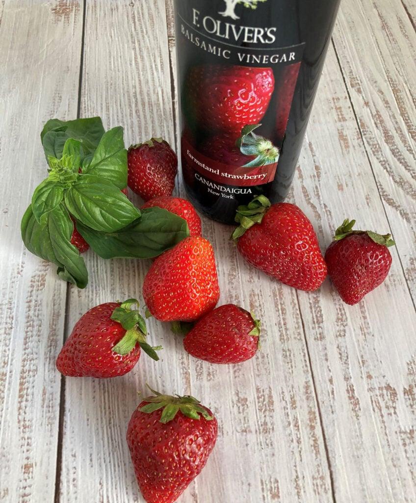 fresh strawberries on a rustic table next to a bottle of balsamic vinegar