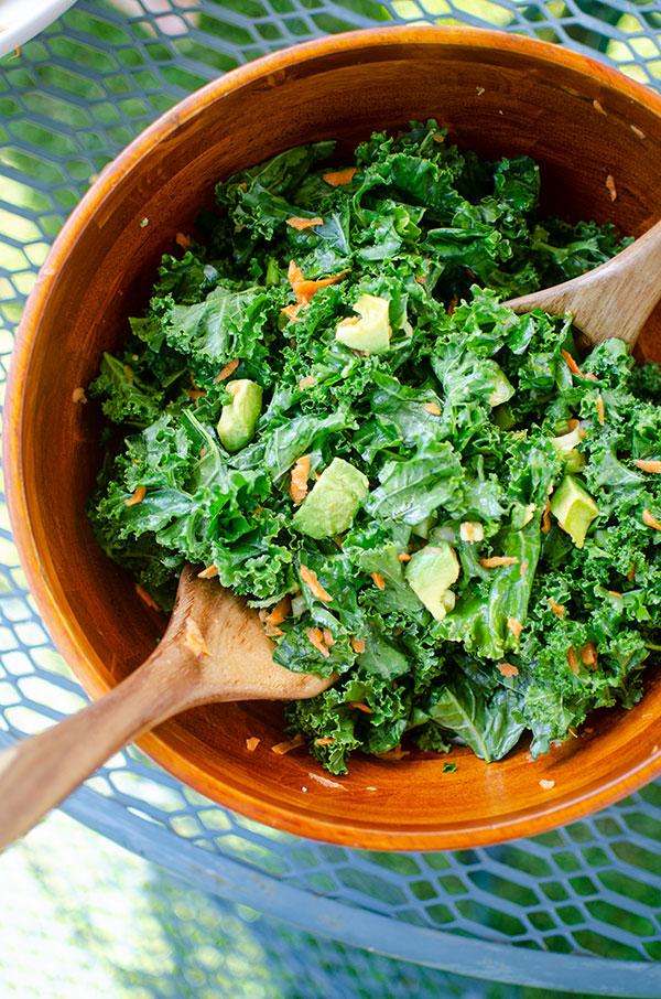 A person enjoying a bowl of avocado kale salad outdoors