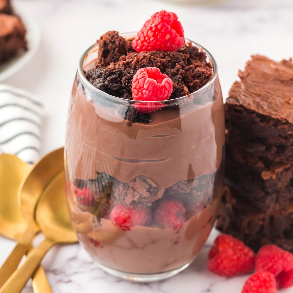 A table set for a party with several glasses of brownie pudding parfaits