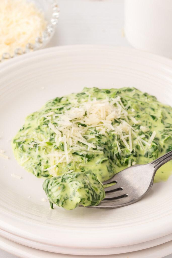 Happy person eating creamed spinach with a fork