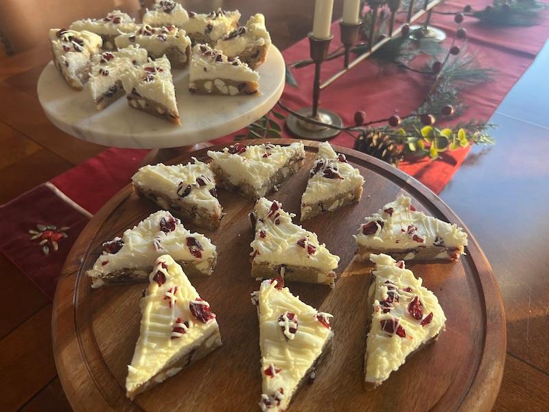 Hands placing cranberry bliss bars into a decorative gift box