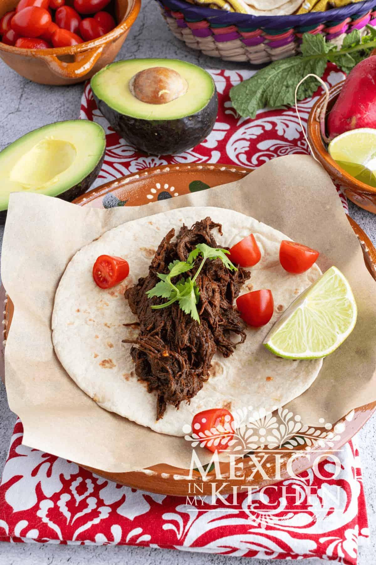 Shredded chili beef roast served in various ways: tacos, rice bowl, and sandwich
