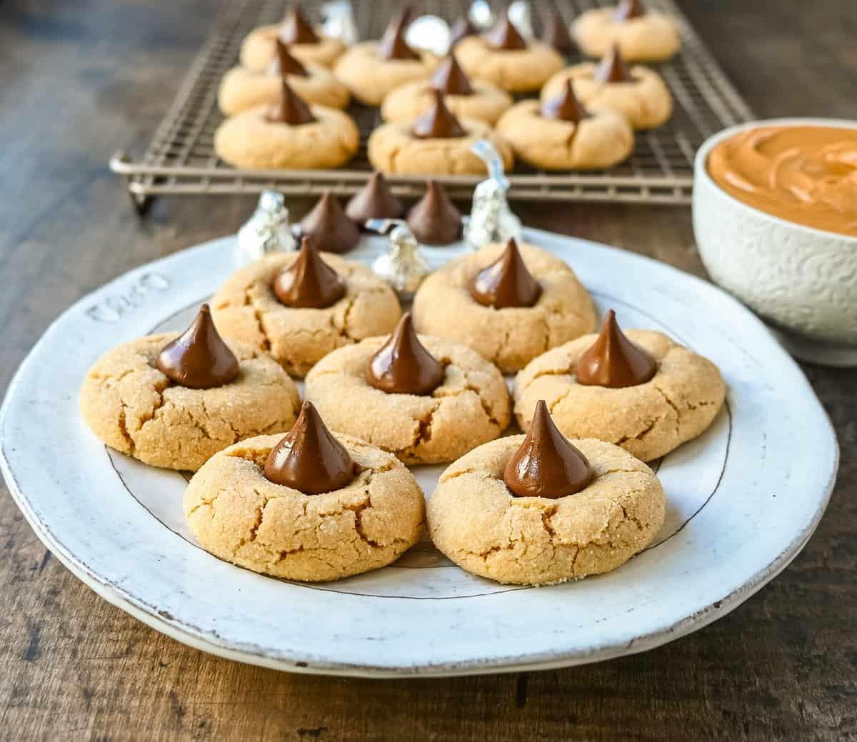 A plate of freshly baked peanut butter blossom cookies with Hershey's Kisses melted on top.