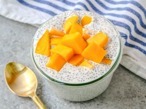 close-up of a spoonful of mango coconut chia pudding with visible chia seeds and mango chunks